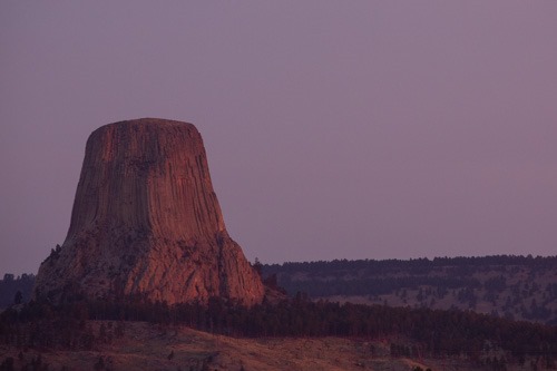 Tall rock tower at sunrise with a purple sky