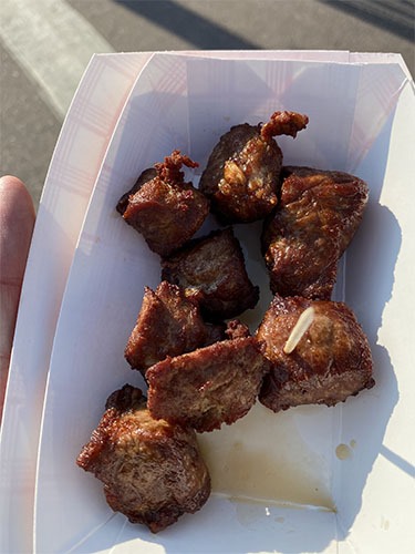 Paper dish of fried meat cubes and a toothpick