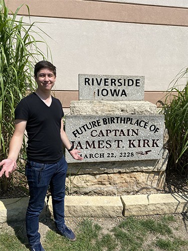 Andrew standing in front of a stone plaque with inscribed with "Riverside Iowa. Future birthplace of Captain James T Kirk. March 22, 2228"