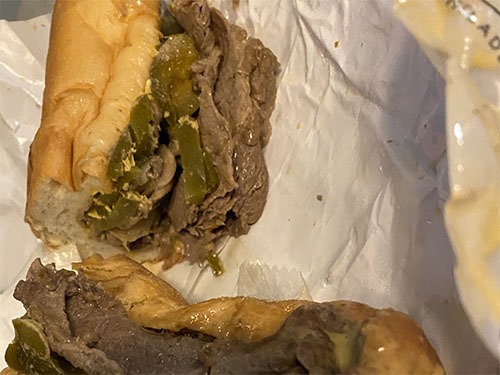 Two halves of a cheesesteak sandwich, more filled than than the one from Pat's. The bun is squished a bit.