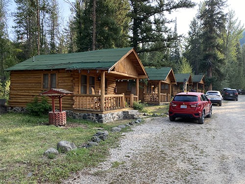 A row of small log cabins with cars parked in front