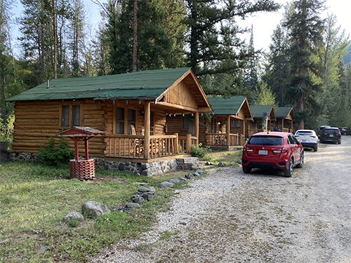 A row of small log cabins with cars parked in front