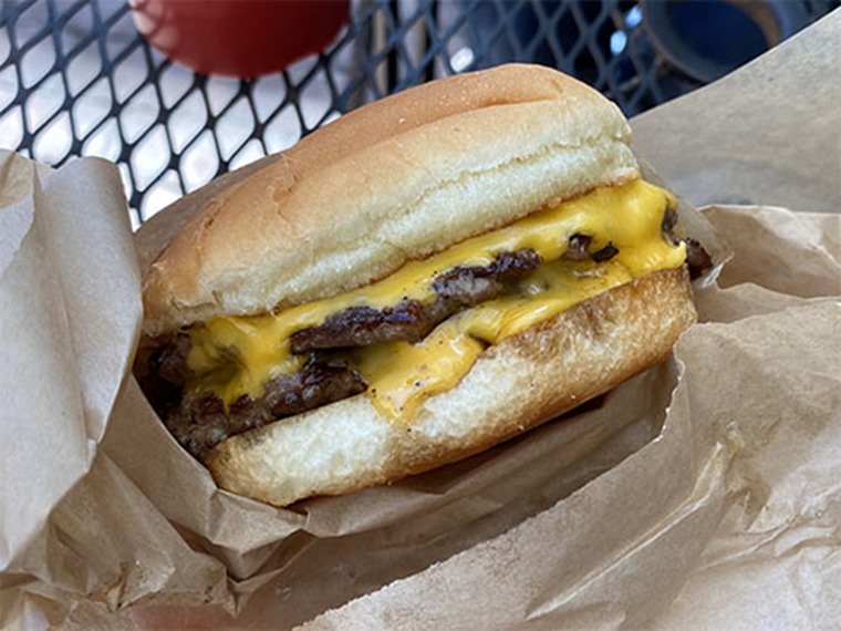 Closeup of a double Tavern cheeseburger in brown wrapping paper