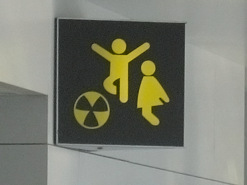 Sign with two sillouette children playing over a beachball that looks like the nuclear symbol.