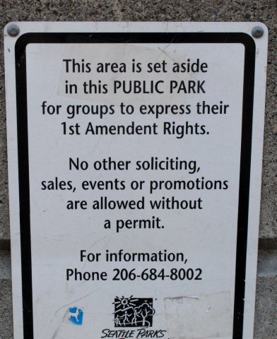 A sign saying "This area is set aside in this PUBLIC PARK for groups to express their 1st Amendment Rights."