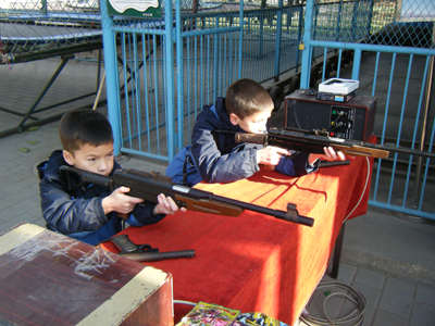 Andrew and Michael shooting rifles at an amusement park.