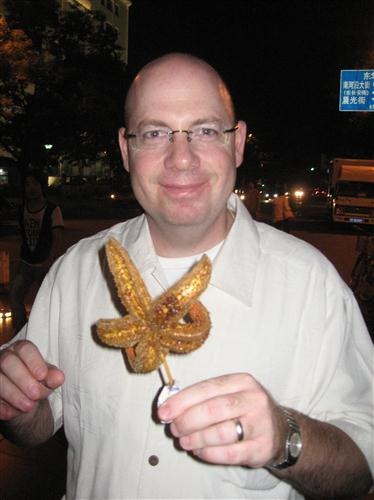 Ari about to tuck into a grilled starfish. To eat these you break off an arm, peel back the tough outer skin, and eat the meaty inside. It looks a bit like cooked finely ground beef but tastes seafoody. Not terrible.