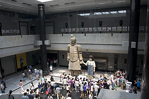 View of 1.5 story terracotta solider marionette with one storey Western doll marionette.