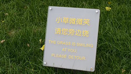 Sign saying "The grass is smiling at you. Please detour."